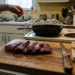 Even slices of raw beef liver on a board with knife, paper towels and cast iron pan