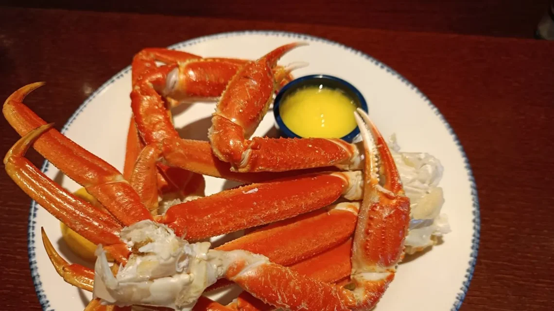 Cooked frozen crab legs with bright orange shells served with melted butter and lemon wedges
