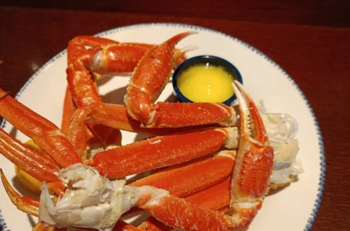 Cooked frozen crab legs with bright orange shells served with melted butter and lemon wedges