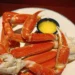Cooked frozen crab legs with bright orange shells served with melted butter and lemon wedges