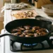 Hand-torn oyster mushrooms browning in one layer in a wide cast iron skillet