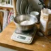 Mixing bowl of flour resting on a digital kitchen scale on a kitchen counter